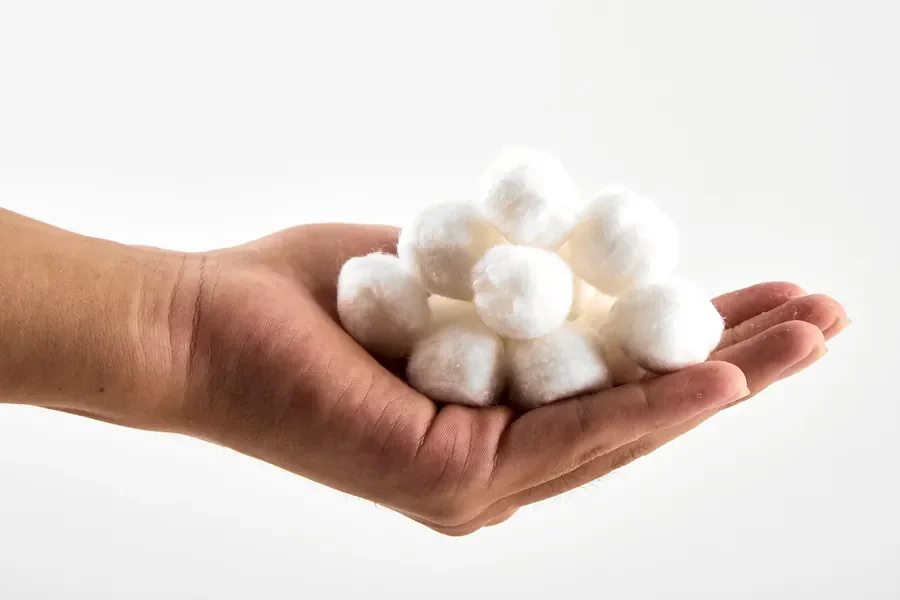 A hand holding a few white cotton balls