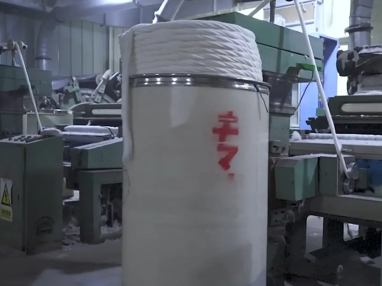 A can of cotton sliver beside a carding machine at the WJ Cotton factory
