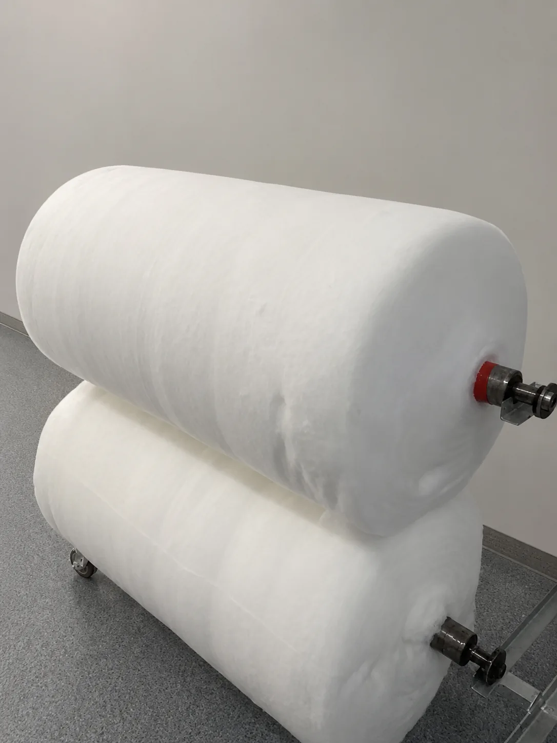 Two large rolls of carded cotton sheet prepared for further converting