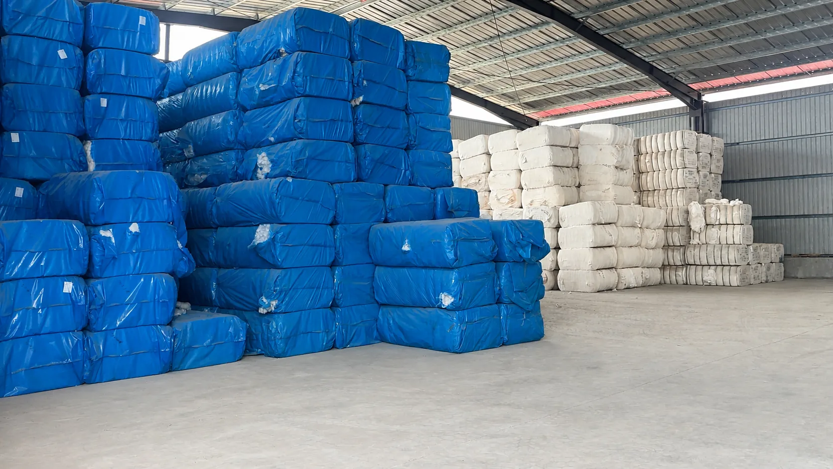 Blue- and white-wrapped raw cotton bales stored inside a raw cotton warehouse